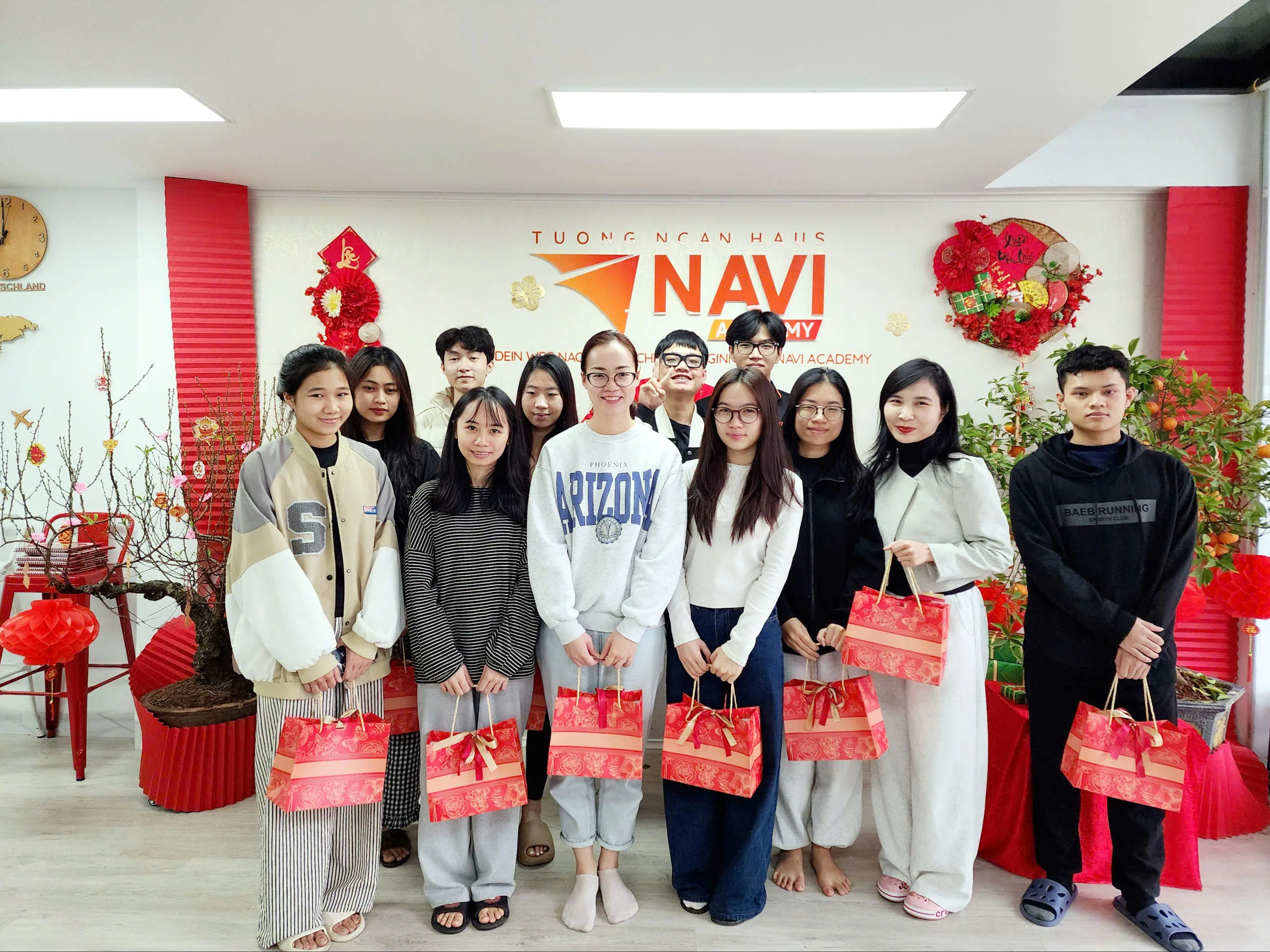 Học viên NAVI Academy đứng thành hàng chụp ảnh, mỗi người cầm một túi quà Tết.